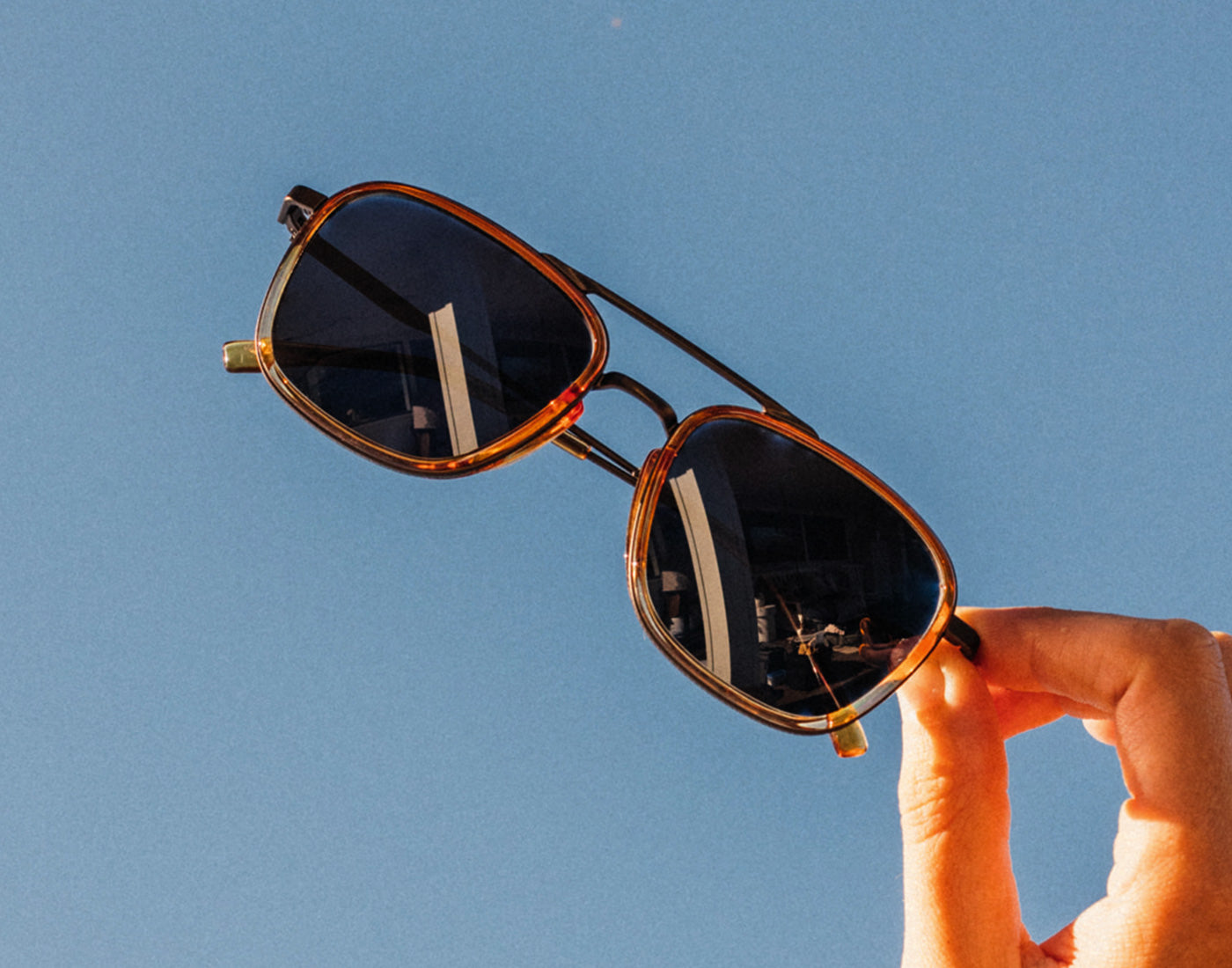 hand holding sunski estero sunglasses in the air