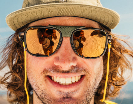 close up of man wearing a hat in sunski ferrata sunglasses