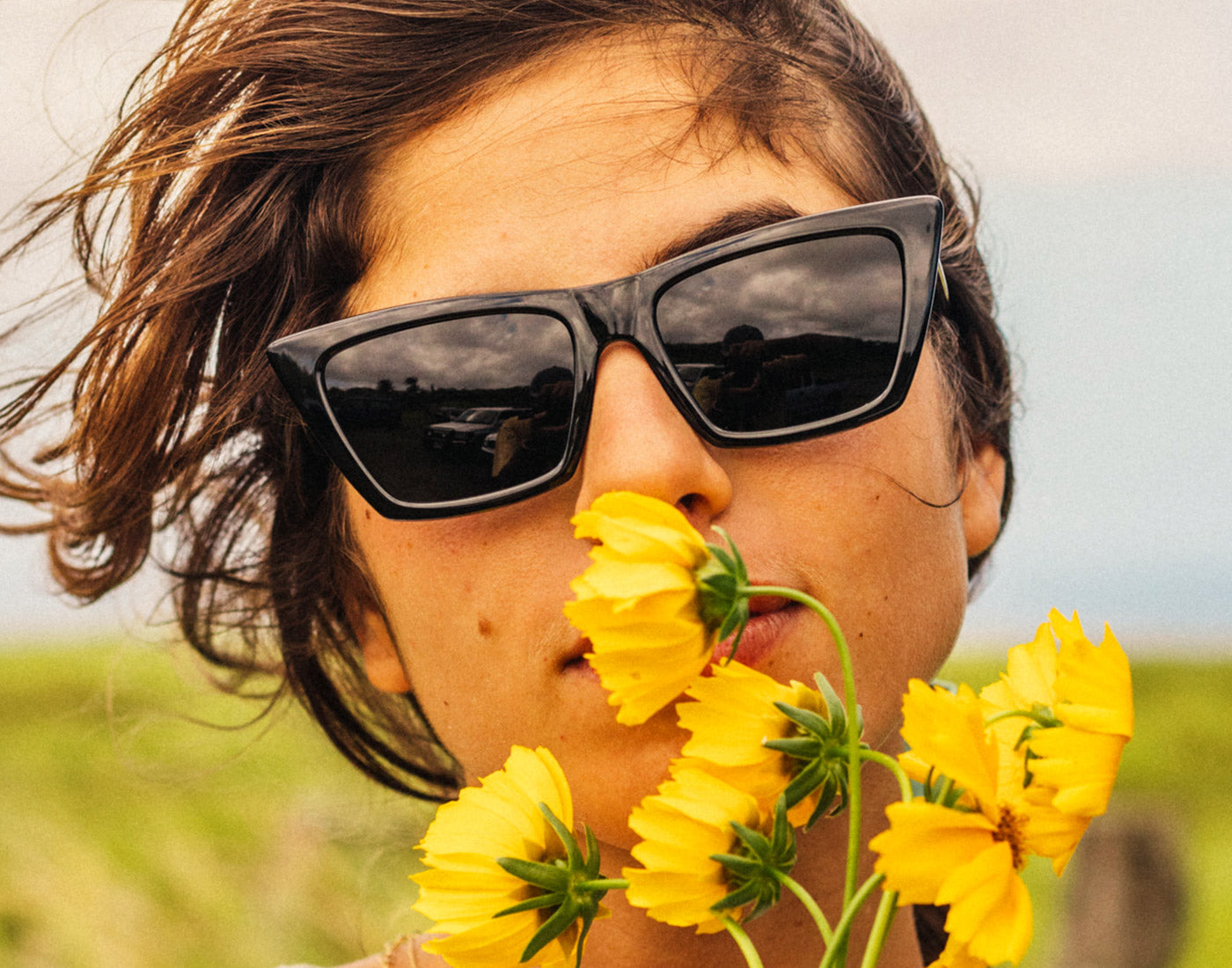 girl smelling flowers wearing sunski fiorella sunglasses