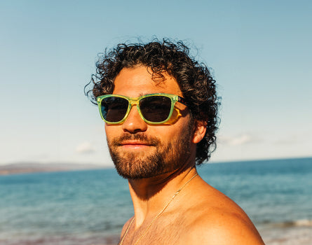 man looking at the camera in front of the ocean wearing sunski headland sunglasses