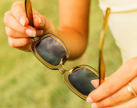 hands holding unfolded pair of sunski lago sunglasses