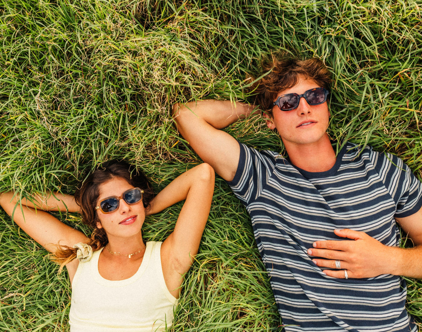 guy and girl laying in the grass wearing sunski lago sunglasses