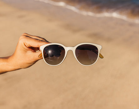 hand holding sunski makani sunglasses on beach
