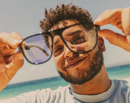 man holding sunski shoreline sunglasses in front of face