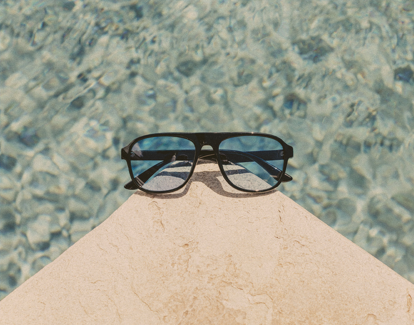 sunski shoreline sunglasses on a pool ledge