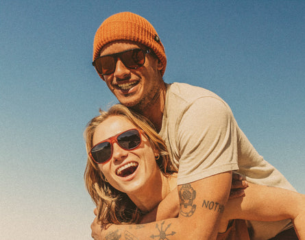 woman giving man piggy back wearing sunski shoreline sunglasses 