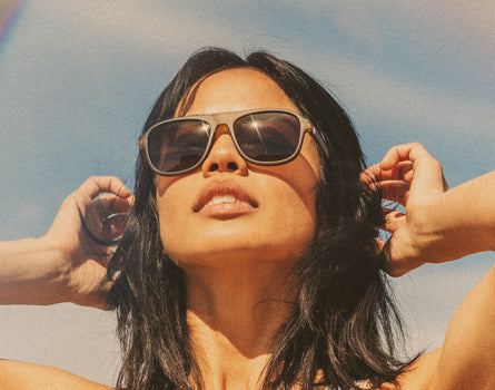 woman tucking hair behind her ears wearing sunski shoreline sunglasses