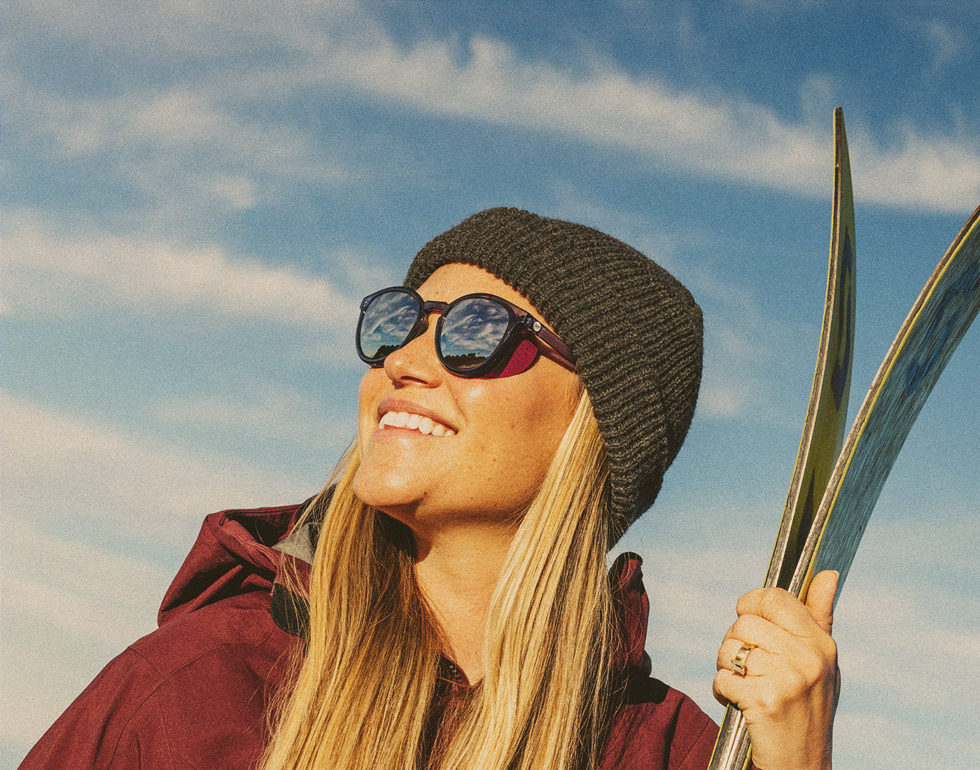 girl holding skis wearing sunski tera sunglasses