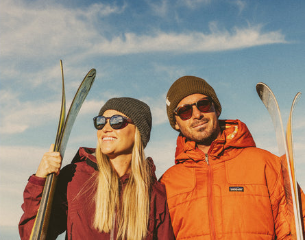 man and woman holding skis wearing sunski tera sunglasses
