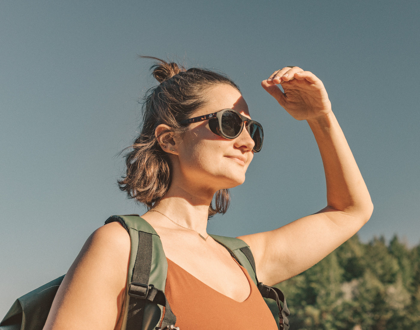 girl holding hand to block the sun wearing sunski treeline sunglasses
