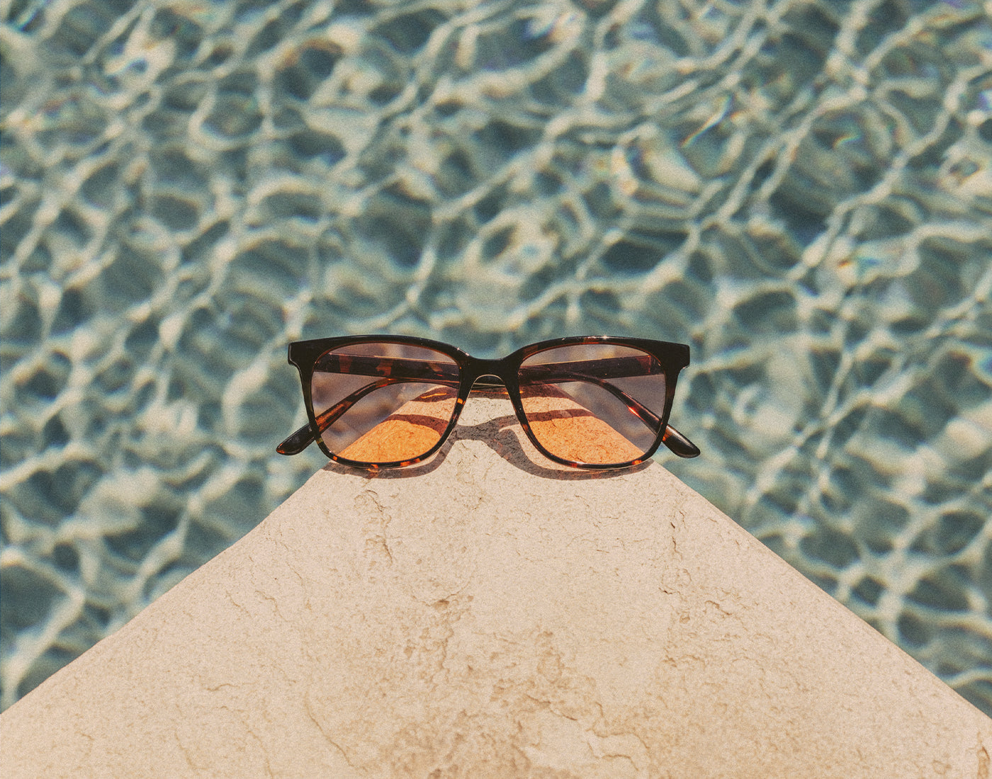 sunski ventana sunglasses on a ledge by a pool 