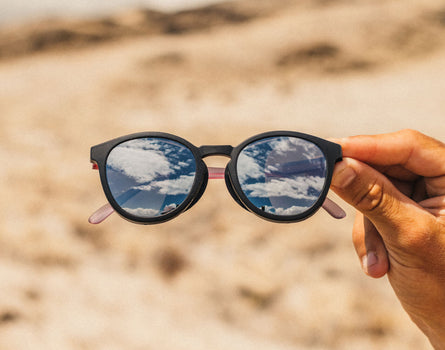 Sunglasses held up with a desert landscape in the background