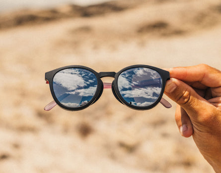 Sunglasses held up with a desert landscape in the background