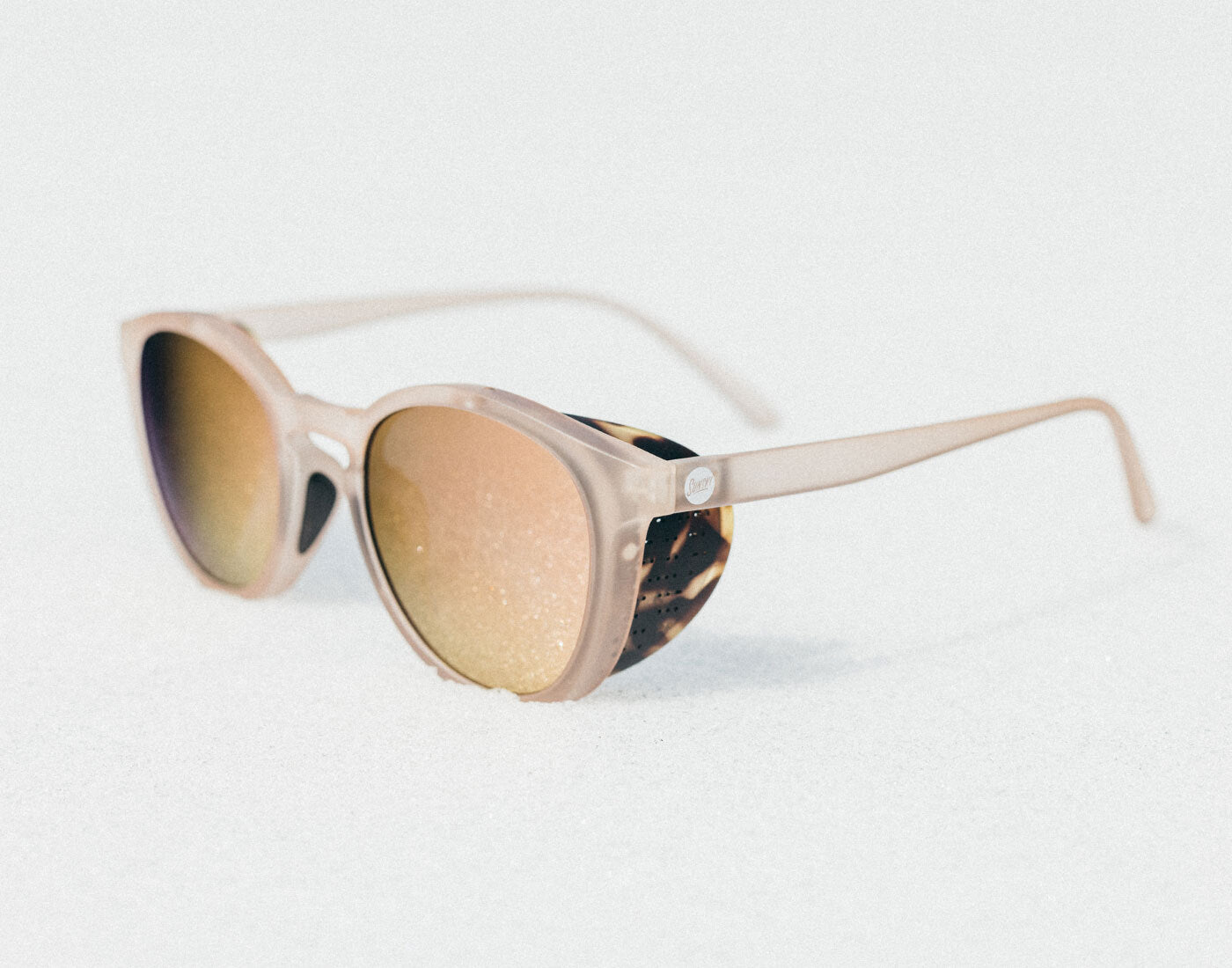 Sunglasses with beige frame and tortoiseshell accents on a light gray background