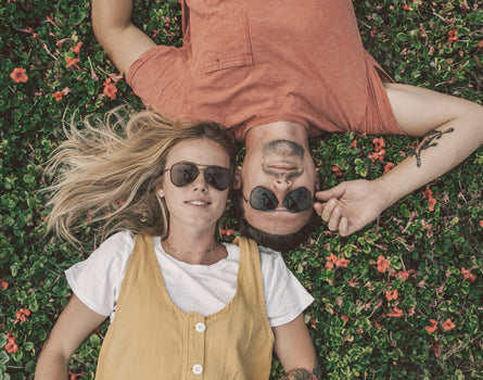 guy and girl laying in the grass wearing sunski astra sunglasses