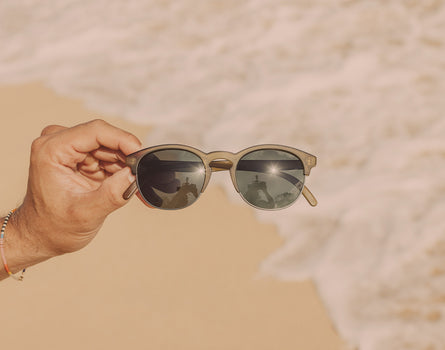 hand holding sunski avila sunglasses on the beach