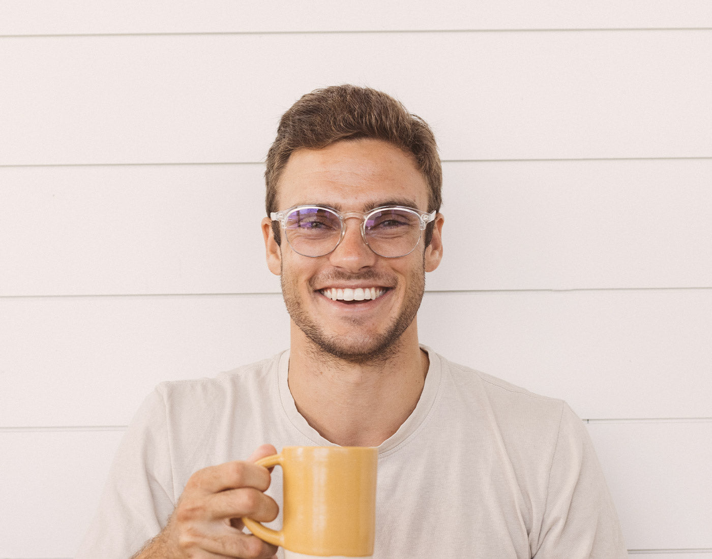 guy holding a cup of coffee laughing wearing sunski avila bluelight glasses