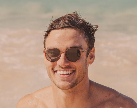 guy smiling on the beach wearing sunski baia sunglasses