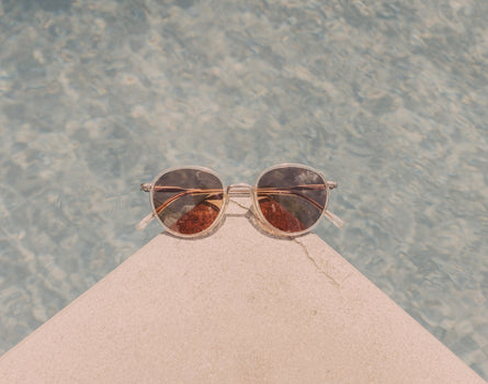sunski baia sunglasses on a corner by a pool