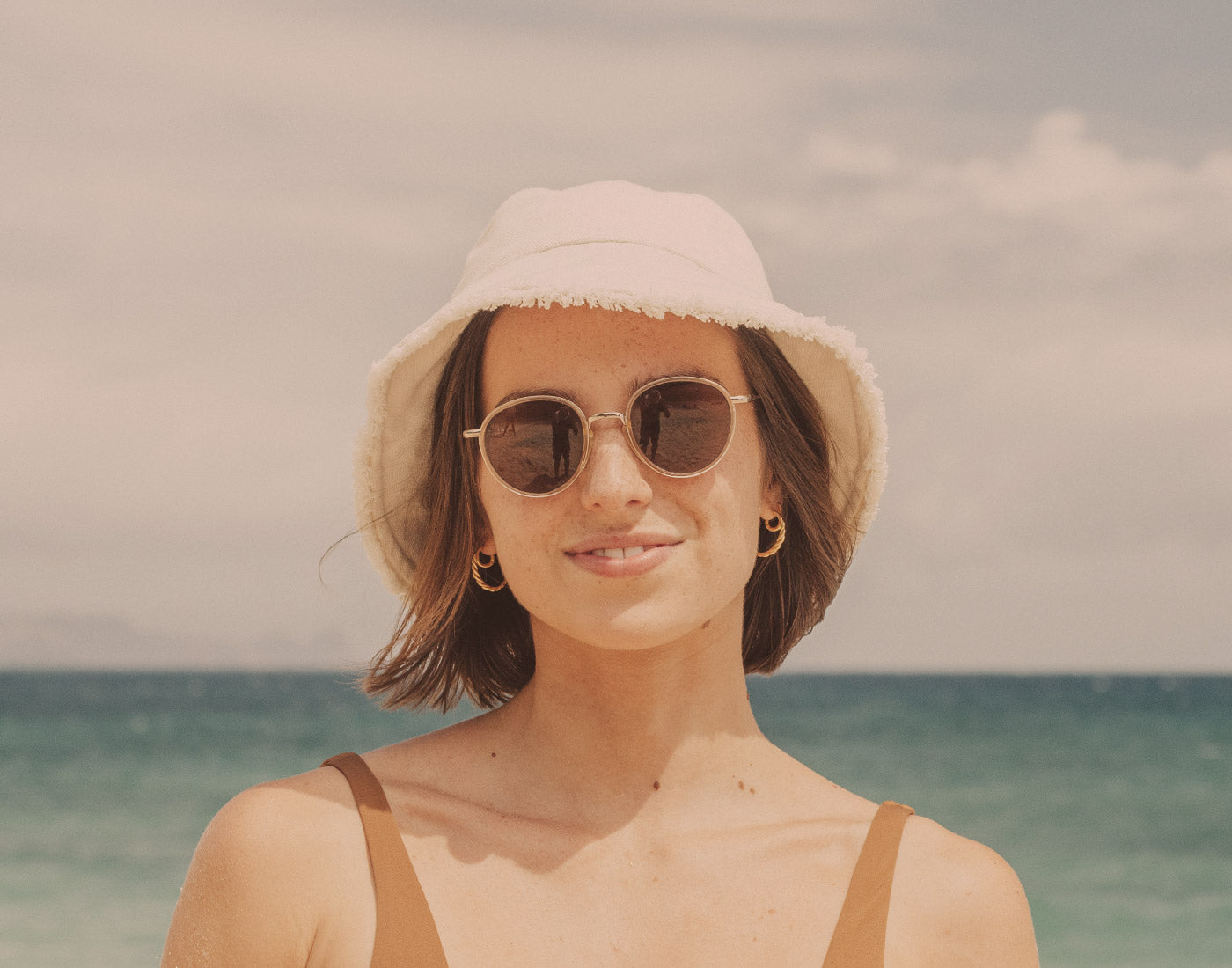 girl in bucket hat wearing sunski baia sunglasses