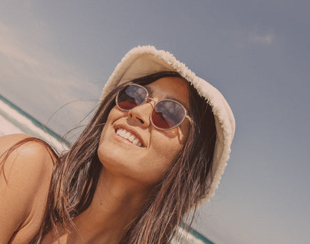 girl looking diagonally in bucket hat wearing sunski baia sunglasses