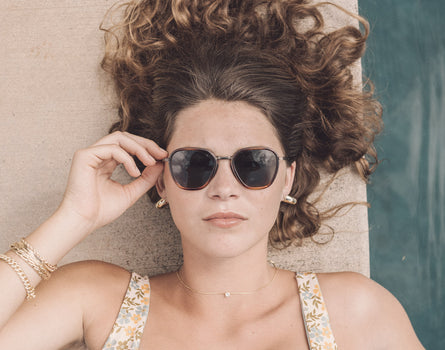 girl laying by pool looking straight wearing sunski bernina sunglasses