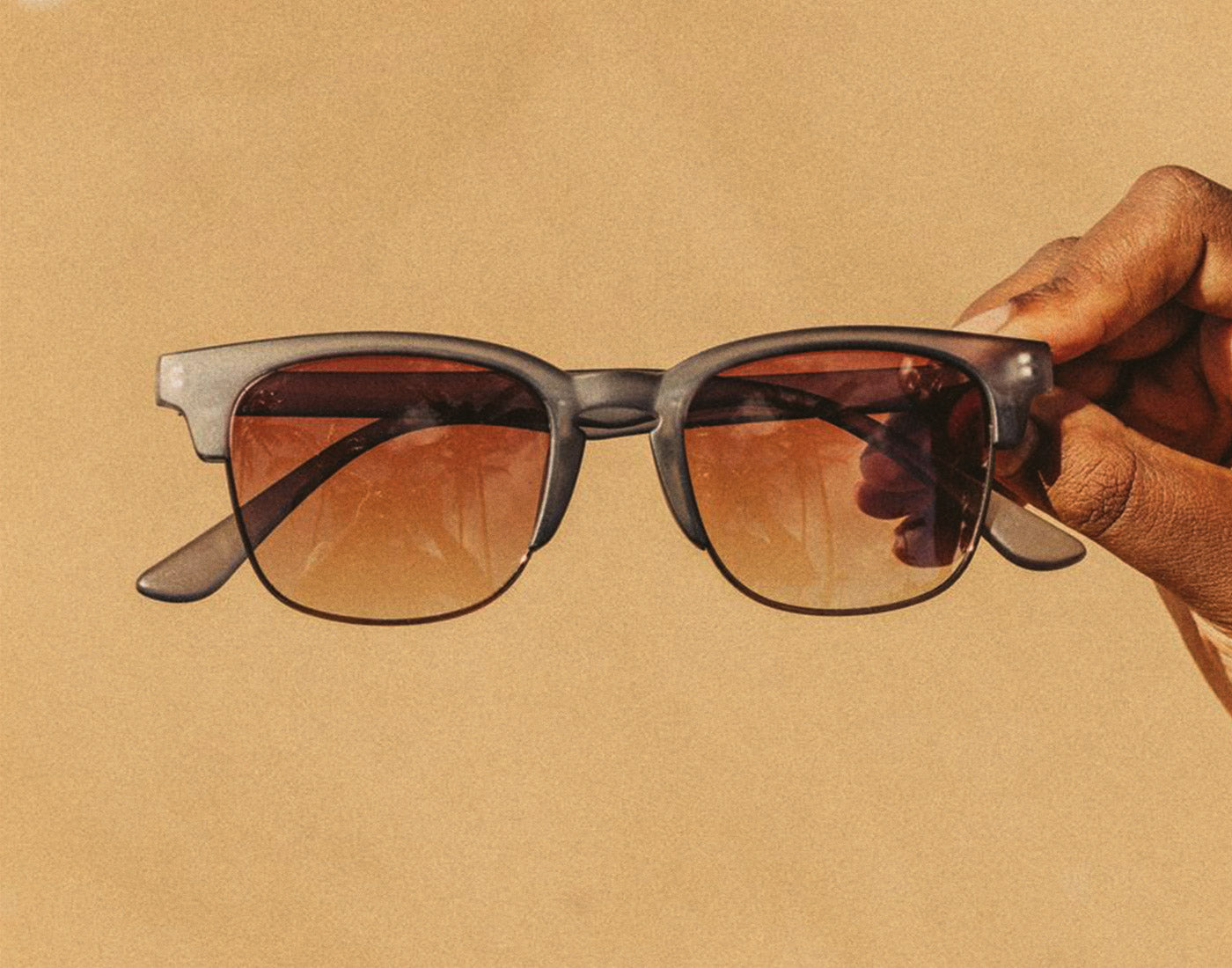 hand holding sunski cambria navy amber sunglasses