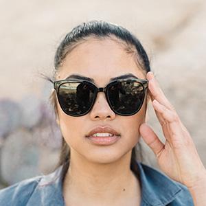 close up of woman holding sunski camina sunglasses on face