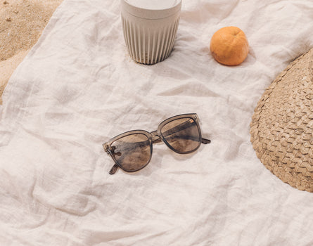 sunski camina sunglasses on a beach towel