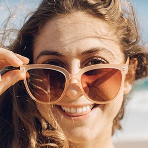 close up of woman tilting sunski camina sunglasses on face