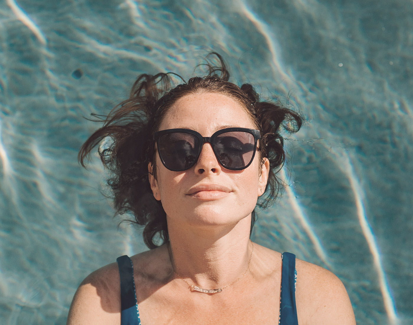 girl floating in pool wearing sunski camina sunglasses
