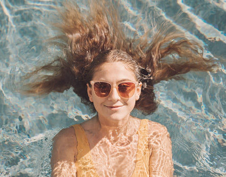 girl smiling in pool wearing sunski camina sunglasses