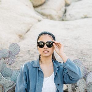 wide shot of woman holding sunski camina sunglasses on face