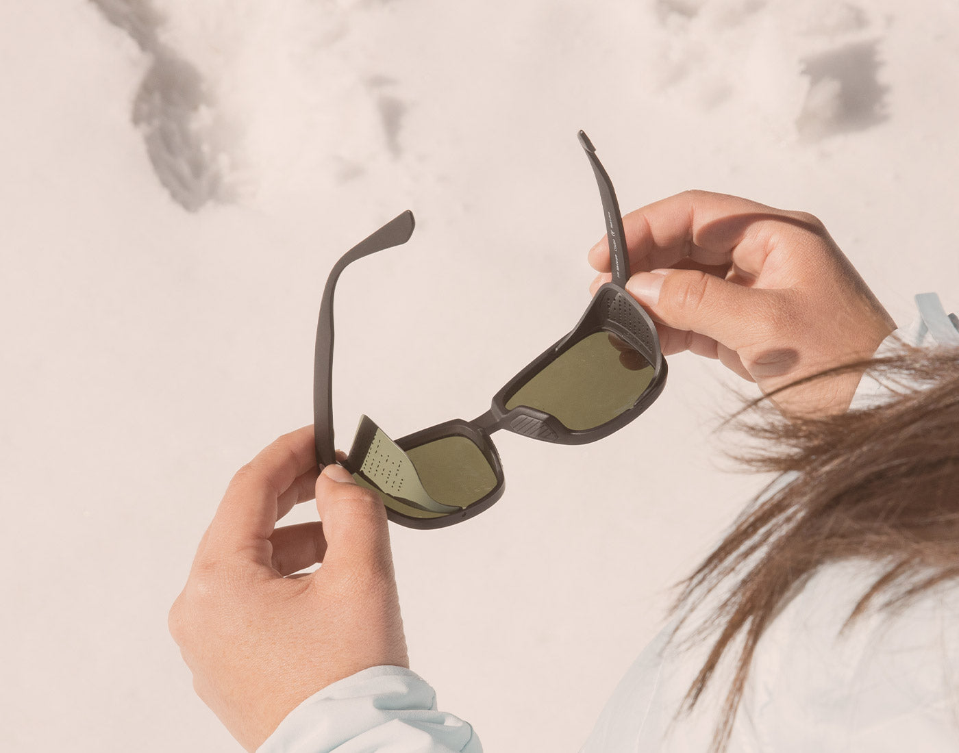 hands holding unfolded sunski couloir sunglasses