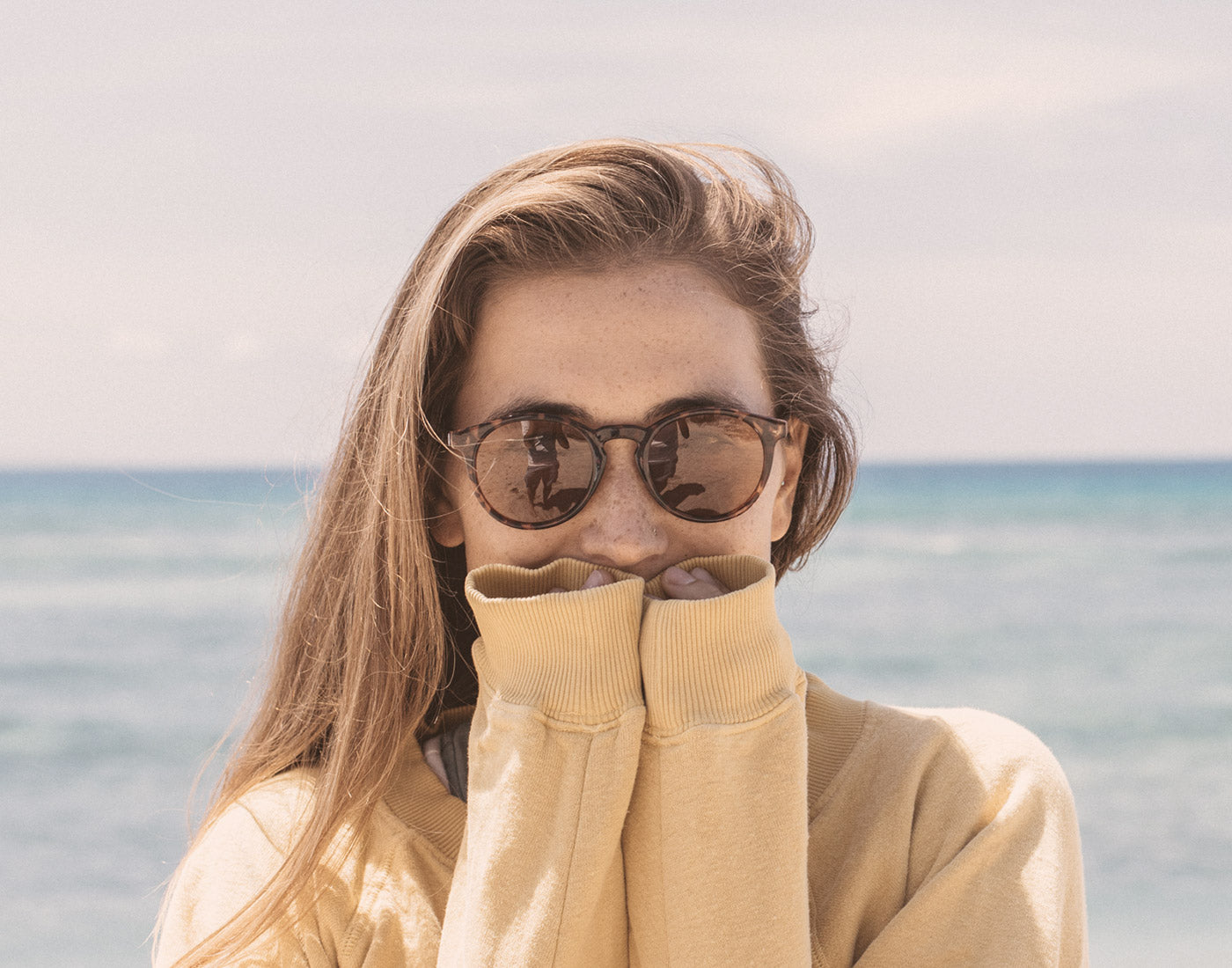 girl covering mouth wearing sunski dipsea sunglasses