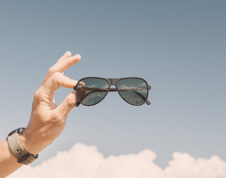 hand holding sunski foxtrot sunglasses in front of sky