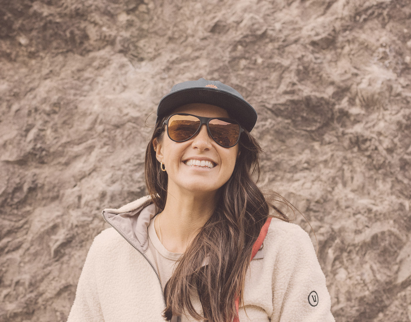 girl standing in front of rock wall wearing sunsk foxtrot sunglasses