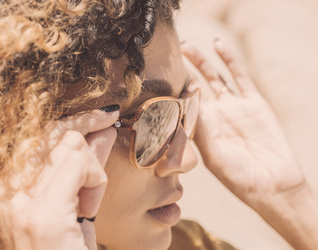 close up profile of girl putting on sunski foxtrot sunglasses