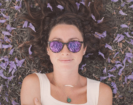 girl laying in the grass wearing sunski makani sunglasses