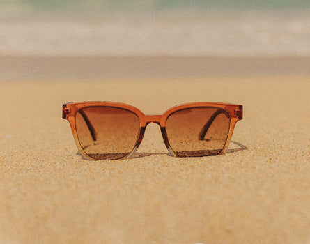 sunski miho sunglasses sitting on sand