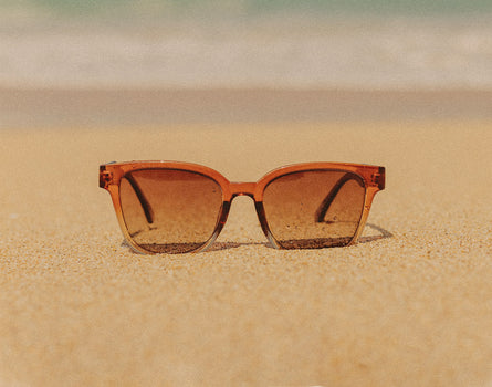sunski miho sunglasses sitting on sand