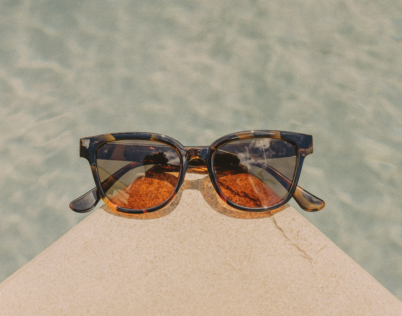 sunski miho sunglasses on side of a pool 