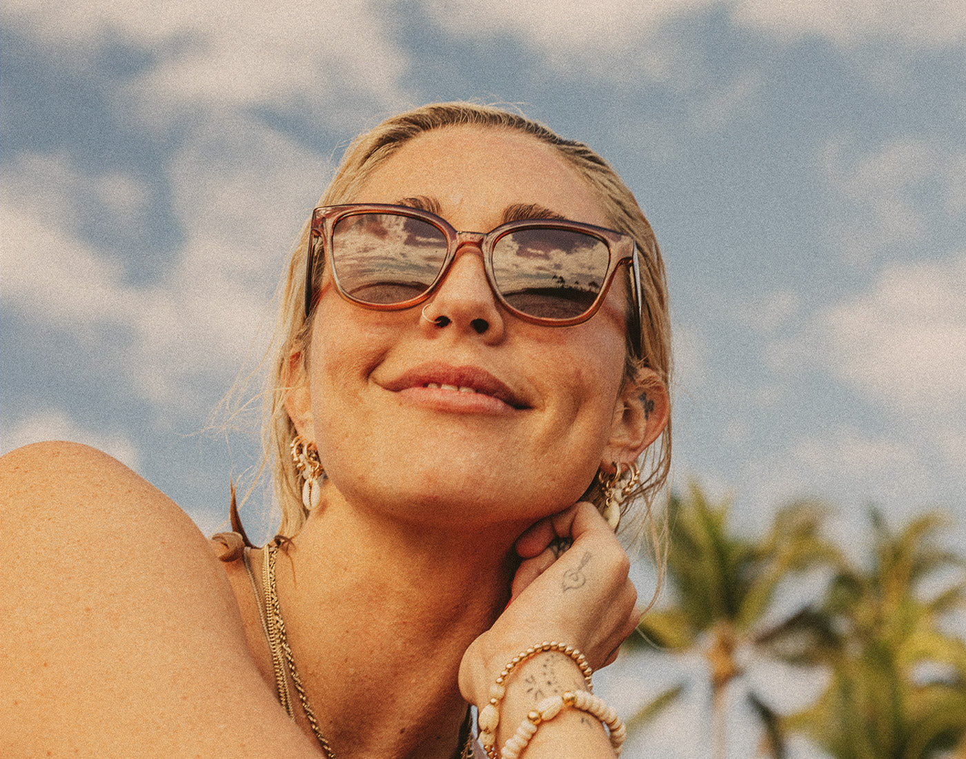 woman smiling with sky in the background wearing sunski miho sunglasses