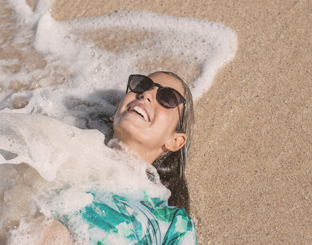 girl in the sand wearing sunski mini dipsea sunglasses