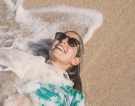 girl in the sand wearing sunski mini dipsea sunglasses