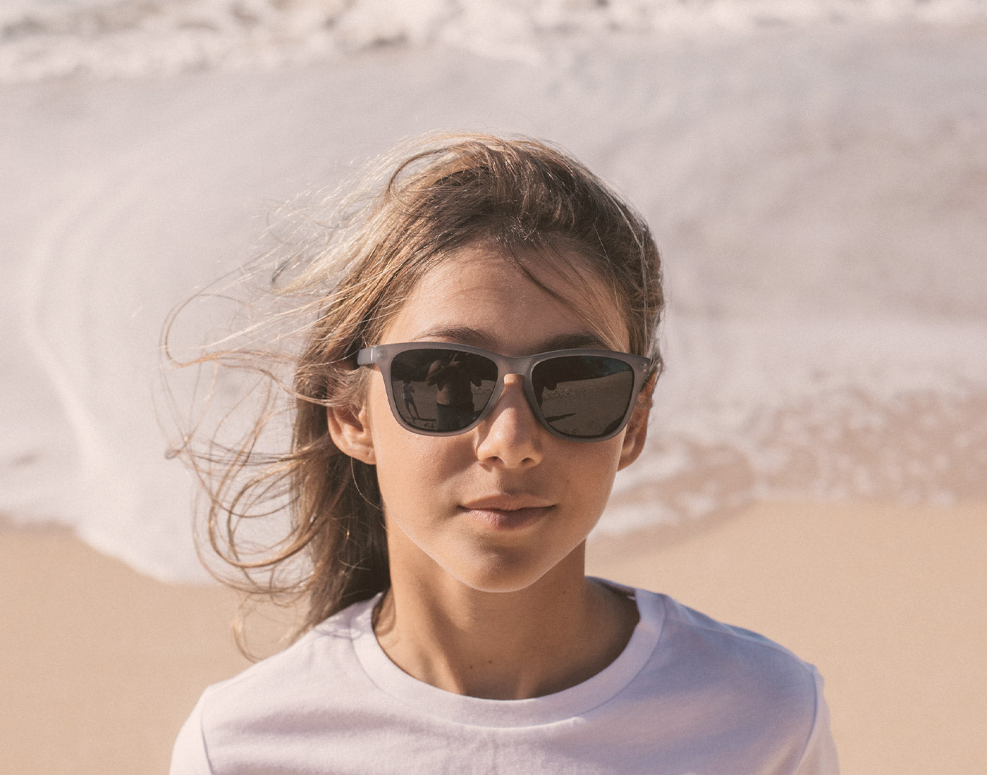 girl on the beach wearing sunski mini headland sunglasses