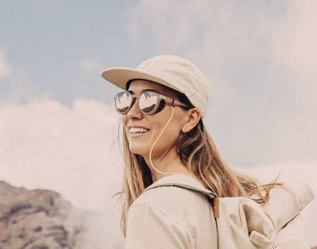 girl in a hat smiling wearing sunski tera sunglasses