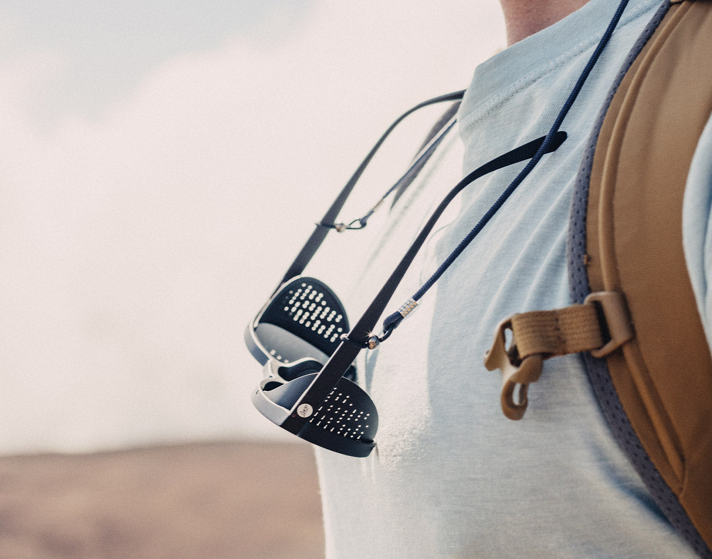 sunski tera sunglasses on a lanyard around someone's neck