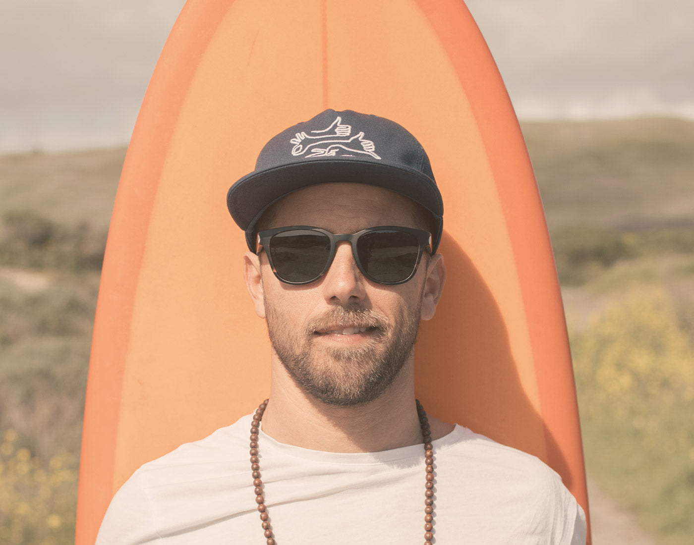 guy standing in front of surfboard wearing sunski topeka sunglasses