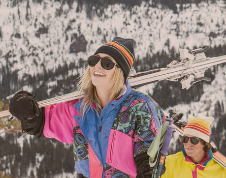 girl holding skiis over shoulder wearing sunski treeline sunglasses